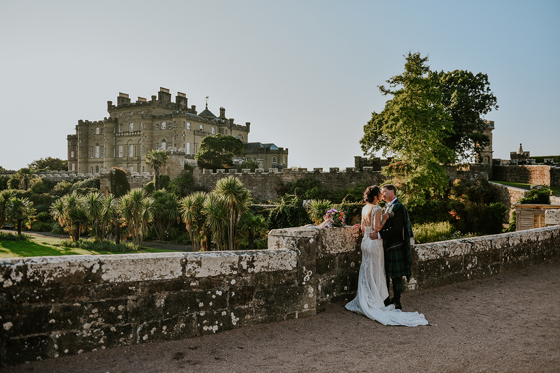 Bride and groom kiss on castle grounds with Culzean Castle in background